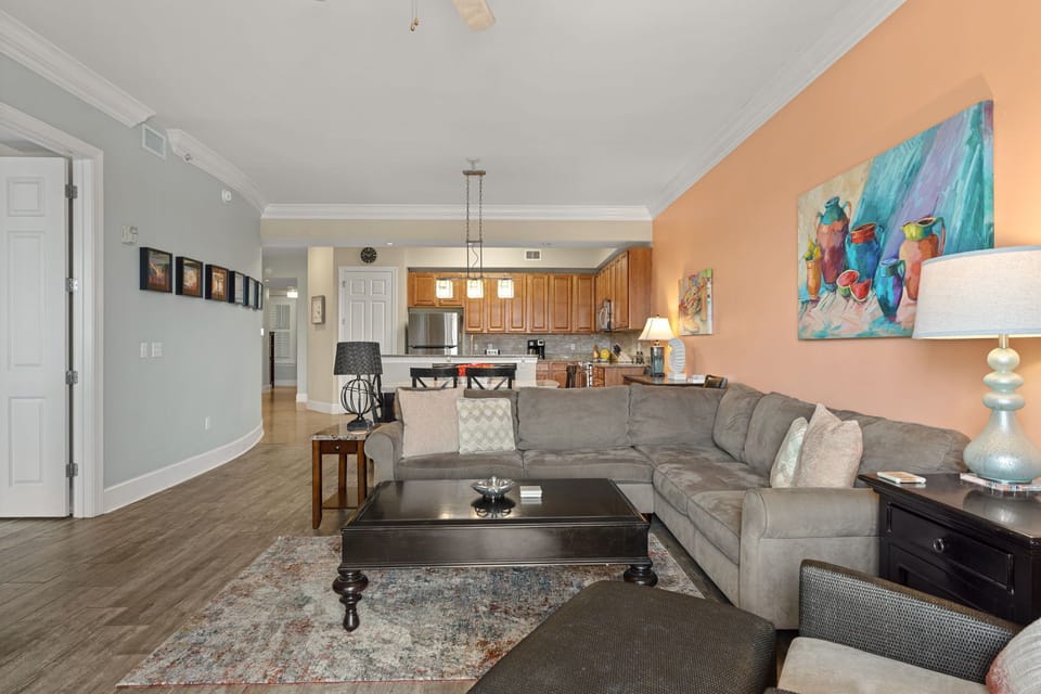 Spacious living area with sectional, enjoy vibrant coastal art, and let the open layout connect you to the fully-equipped kitchen.