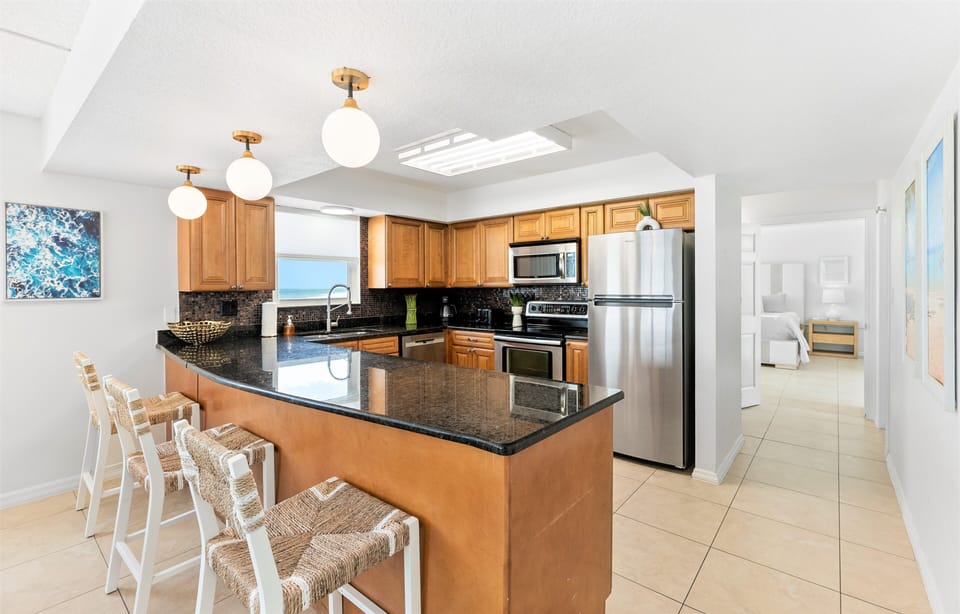Beautiful open concept kitchen with granite counters and a view of the ocean while cooking!