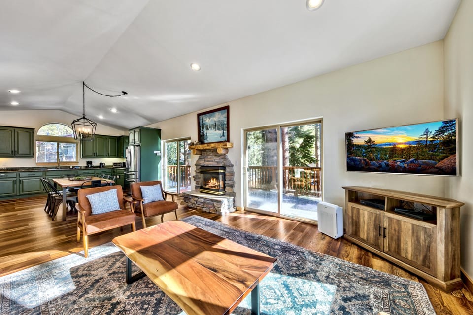 Relax in your spacious living area with warm wood accents, cozy fireplace, and seamless flow to the kitchen and outdoor deck.