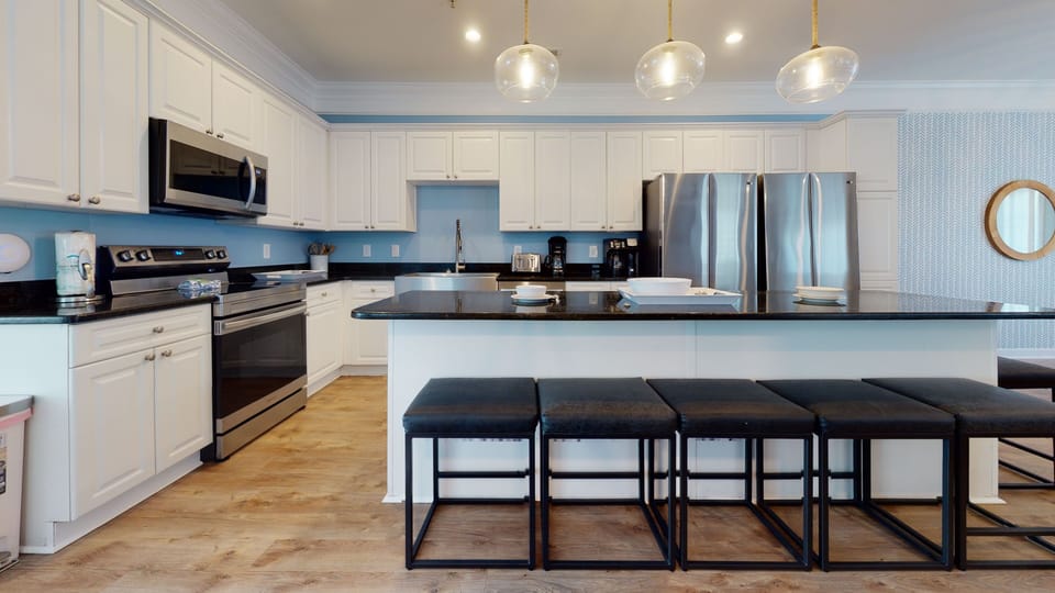 Fully equipped with stainless steel appliances and a sleek island bar.