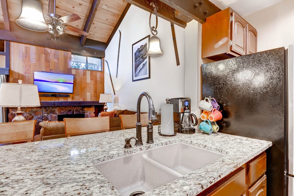 Your mountain retreat kitchen awaits with granite counters, coffee station, and cozy fireplace creating the perfect après-ski atmosphere.