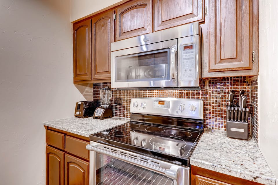 Your fully equipped kitchen features granite countertops, mosaic backsplash, and modern appliances for creating memorable meals during your stay.