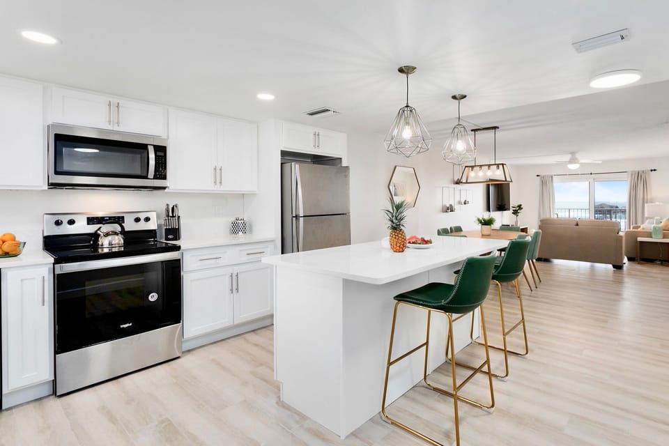 Fully upgraded kitchen equipped with stainless steel appliances, quartz countertops, and bar seating.