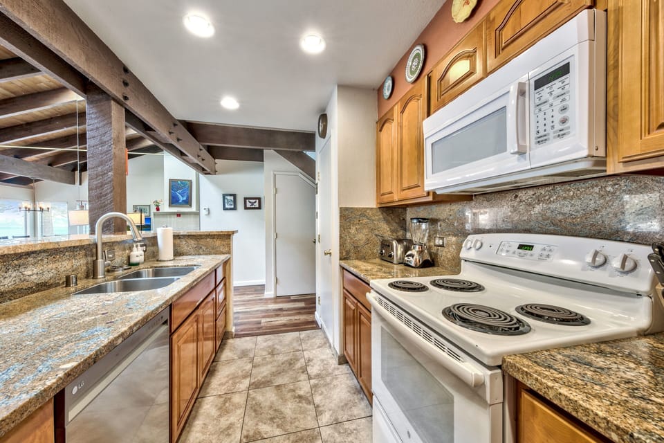 This fully-equipped kitchen features granite countertops, modern appliances, and rustic wood beams, perfect for creating memorable meals together.