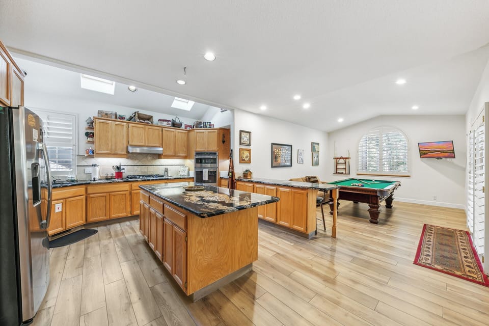 Your spacious open-plan kitchen flows seamlessly into the game room, perfect for preparing meals while friends enjoy billiards.