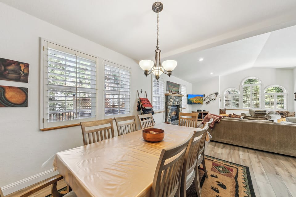 Gather around your spacious dining table where warm wood meets natural light streaming through plantation shutters, creating the perfect setting for memorable meals.