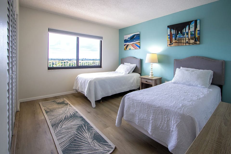 Bright guest bedroom has coastal charm and stunning window views.