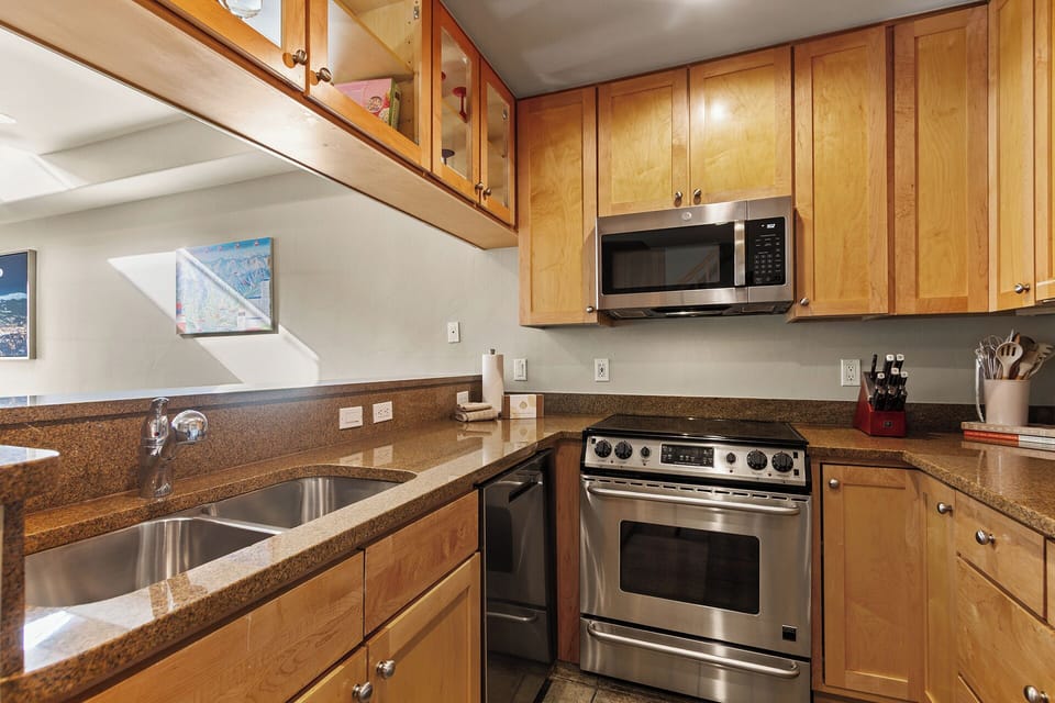 Cook with ease in your fully equipped kitchen, featuring warm wood cabinetry, granite countertops, and modern stainless steel appliances for memorable meals.