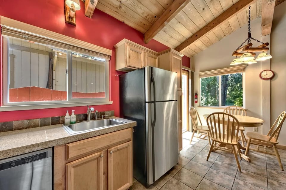 Your fully equipped kitchen features rustic exposed beams, stainless steel appliances, and a cozy dining nook with forest views.