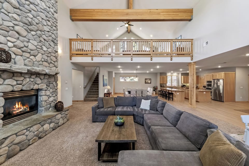 Gather around the stone fireplace in your expansive great room, where soaring ceilings and warm wood create the perfect mountain retreat atmosphere.
