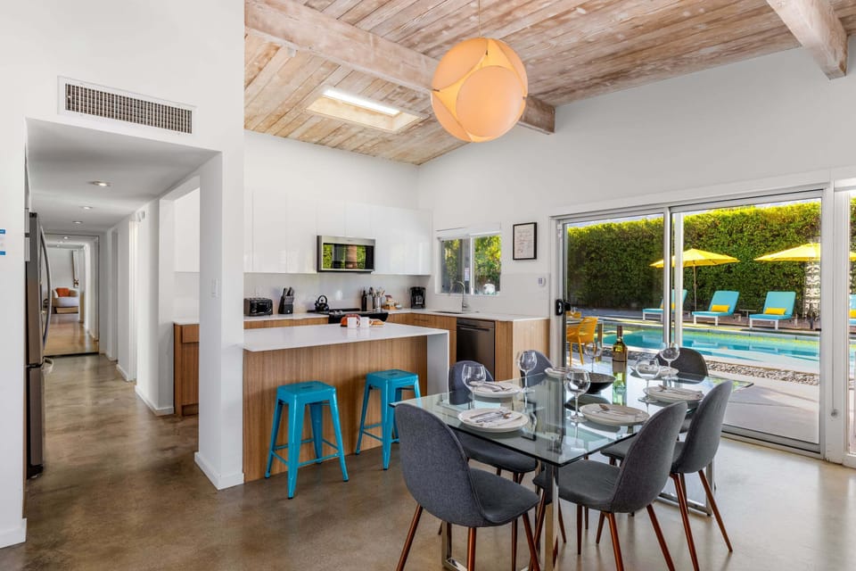 Your open-concept kitchen flows seamlessly to the dining area, where poolside views through floor-to-ceiling windows create the perfect backdrop for meals together.