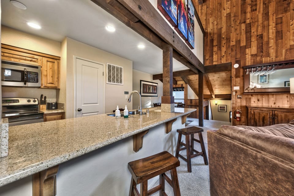 Your open-concept kitchen flows seamlessly into the living area, featuring granite countertops and rustic wood beams that create mountain charm.