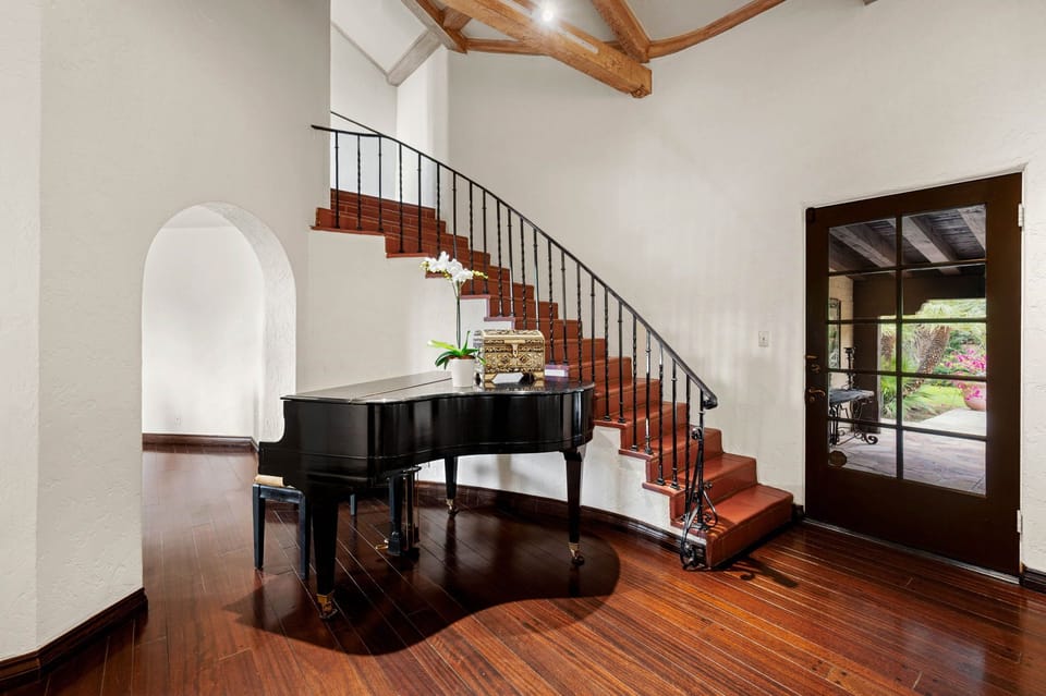 A polished grand piano awaits your musical moments in this elegant entryway, where rich wood beams and gleaming floors invite you to unwind beneath soaring ceilings.