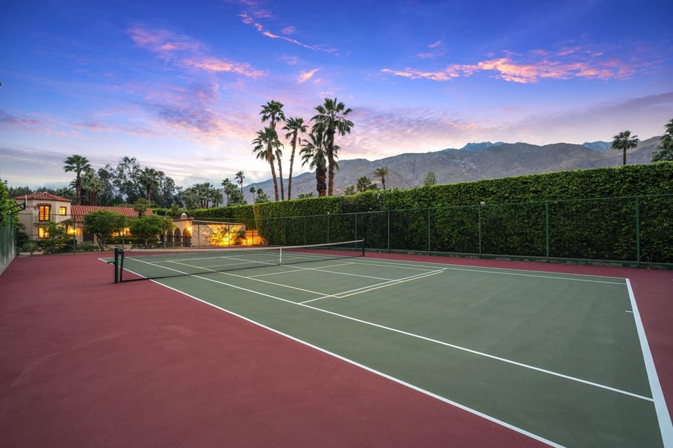 Private tennis court framed by palm trees and mountain views, perfect for an active getaway at this desert retreat.