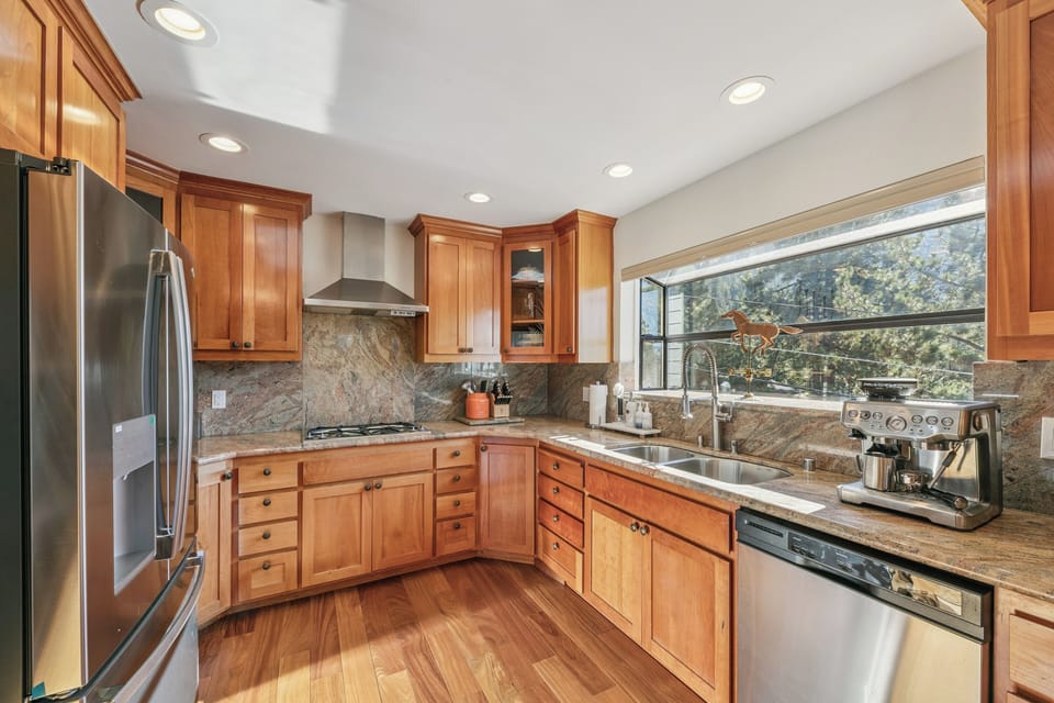 Cook your favorite meals in this beautifully appointed kitchen with warm wood cabinets, granite counters, and forest views through the large window.