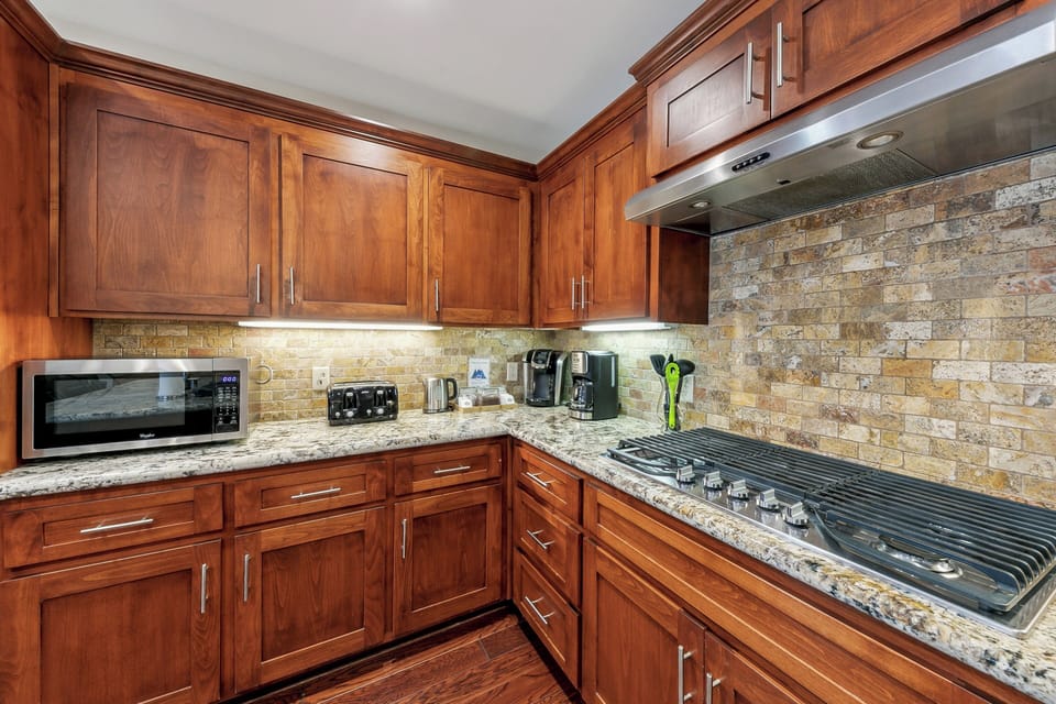 Your gourmet kitchen features rich wood cabinetry, granite countertops, and modern appliances perfect for creating memorable meals during your stay.