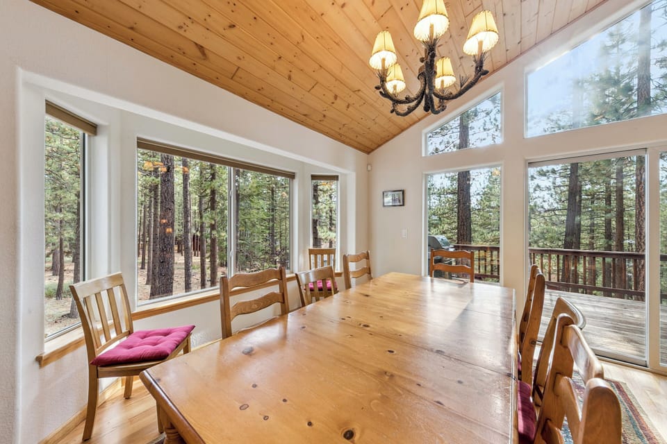 Gather around this stunning wood dining table where forest views through floor-to-ceiling windows create the perfect backdrop for memorable meals together.