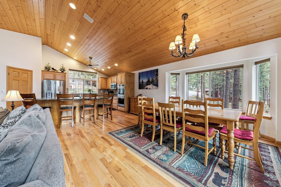 Gather around this spacious dining table where you'll share memorable meals beneath warm wood ceilings and forest views streaming through windows.