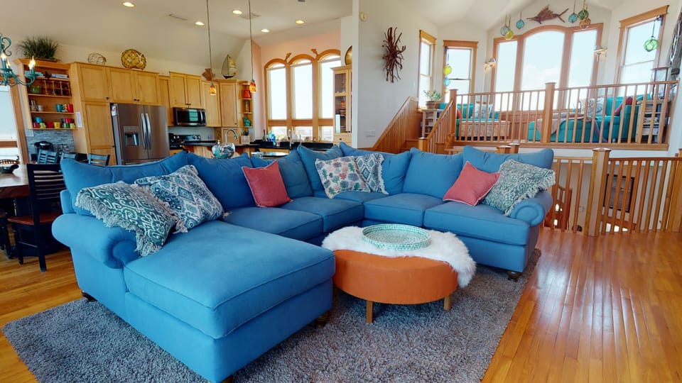 Living room with ships watch above, and kitchen behind