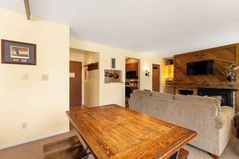 Unwind in your comfortable living room featuring a cozy fireplace, plush seating, and a warm wooden accent wall—your perfect home base after a day exploring the mountains.