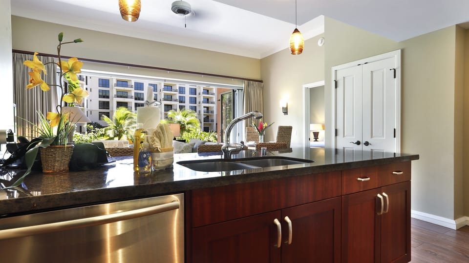 The kitchen features sleek granite countertops & bar stools 