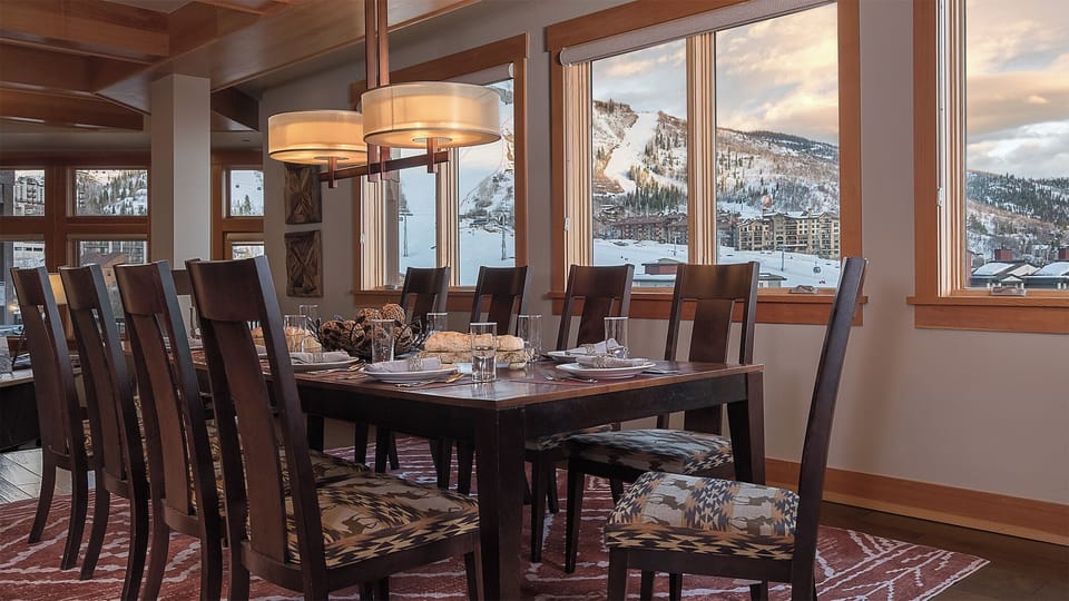 Gather with loved ones around this spacious dining table while soaking in breathtaking mountain views through floor-to-ceiling windows—your perfect mountain retreat awaits.