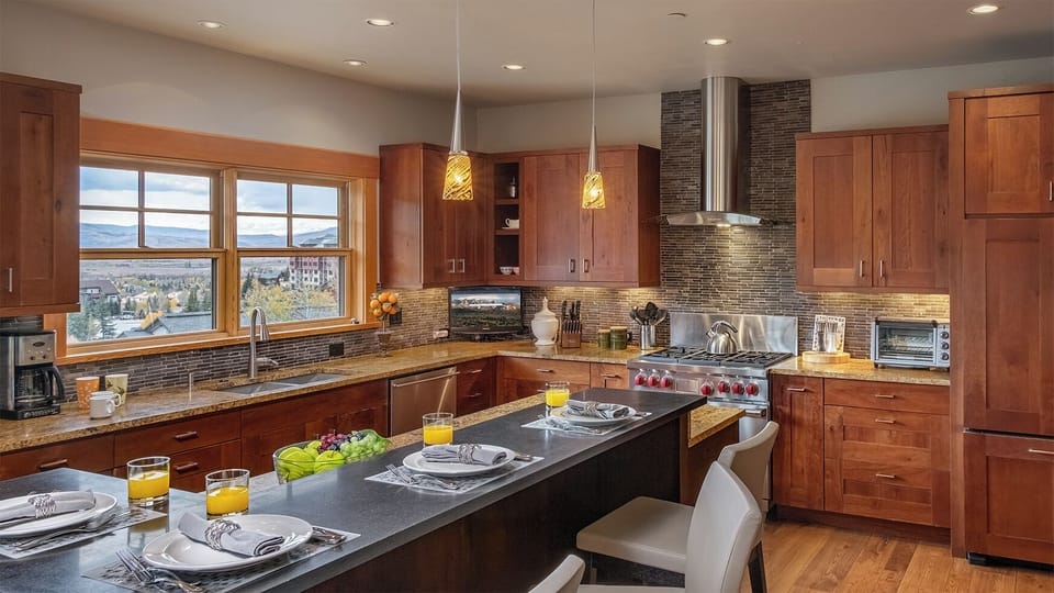 Imagine cooking your favorite meals in this spacious, sunlit kitchen with granite counters, stainless-steel appliances, and stunning mountain views through large windows.