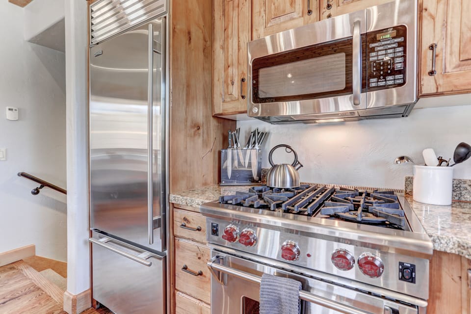 Gourmet display kitchen with Viking refrigerator, 5-burner gas stove, granite counters, and island with 4-bar seats