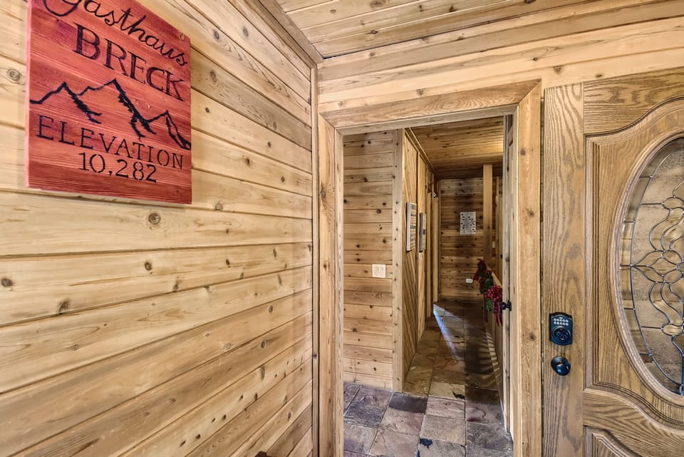 Wooden interior hallway with a doorway, slate flooring, and a sign on the wall reading "Gasthaus Brick Elevation 10,282.
