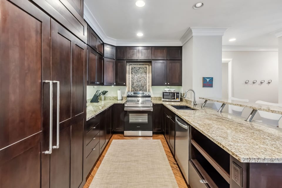 Your gourmet kitchen awaits with granite countertops, stainless steel appliances, and rich dark cabinetry perfect for preparing memorable meals.