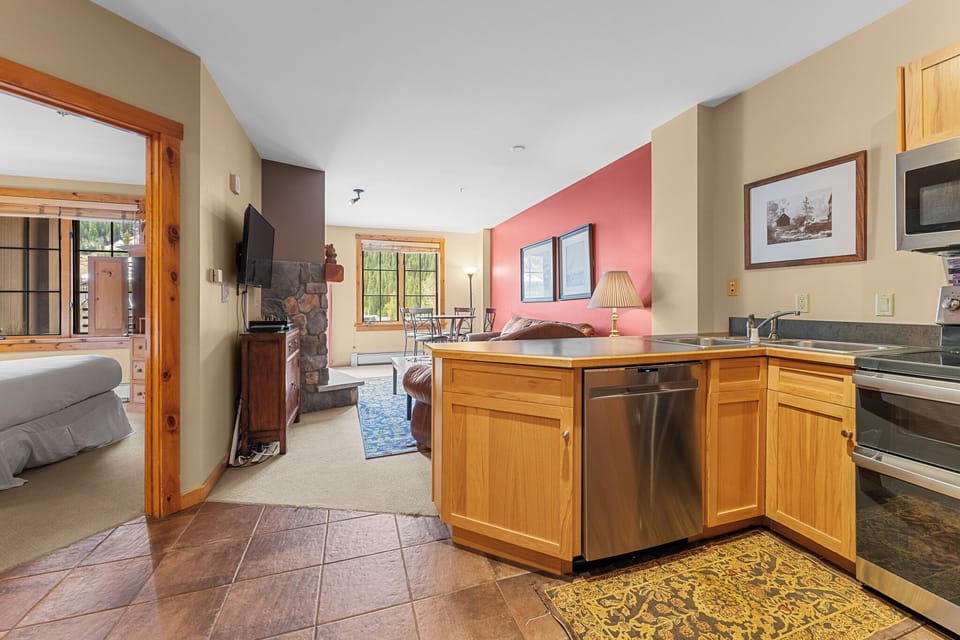 Your open-concept suite blends kitchen, living and bedroom areas with warm wood accents, stone fireplace, and mountain lodge charm throughout.
