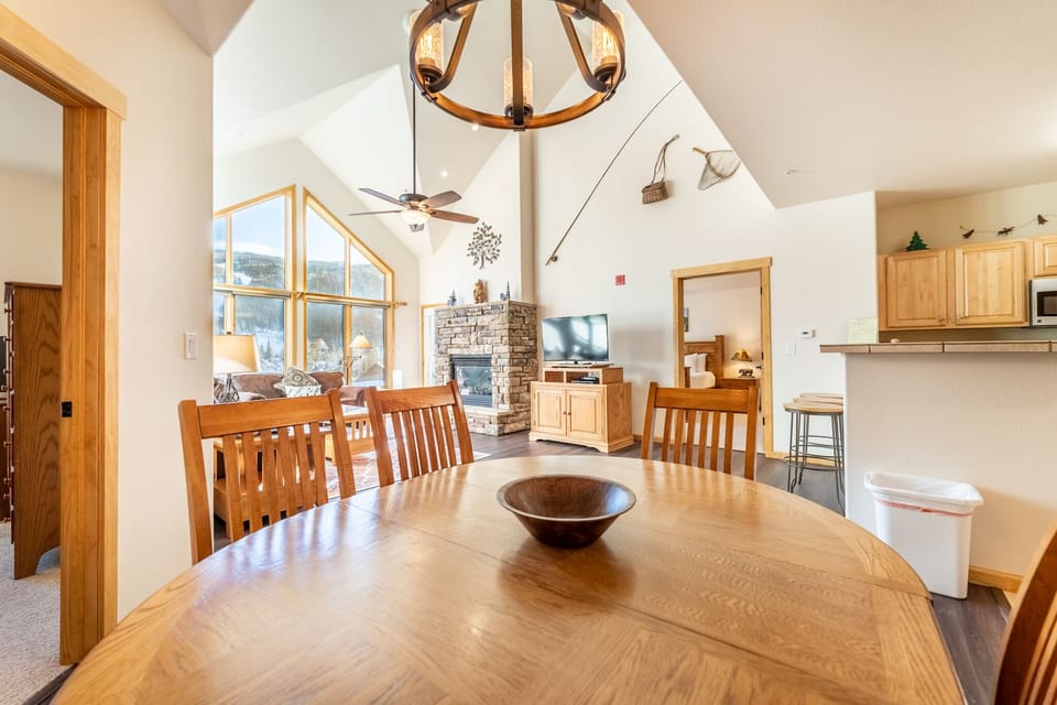 Gather around this beautiful dining table where warm wood and soaring ceilings create the perfect space for memorable meals together.
