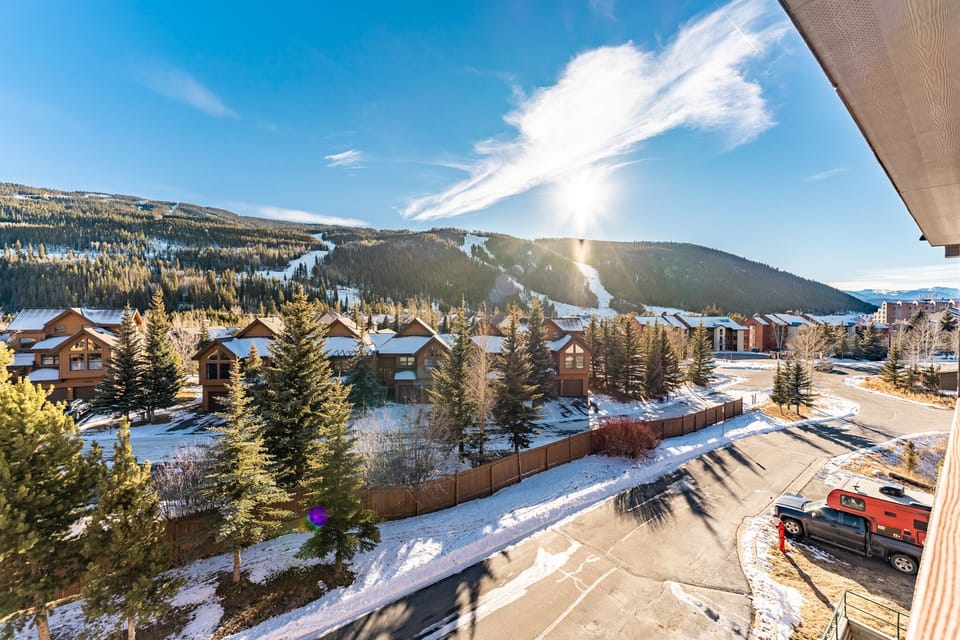 Mountain resort community with ski slopes visible across snow-covered landscape and residential chalets nestled among evergreen trees.