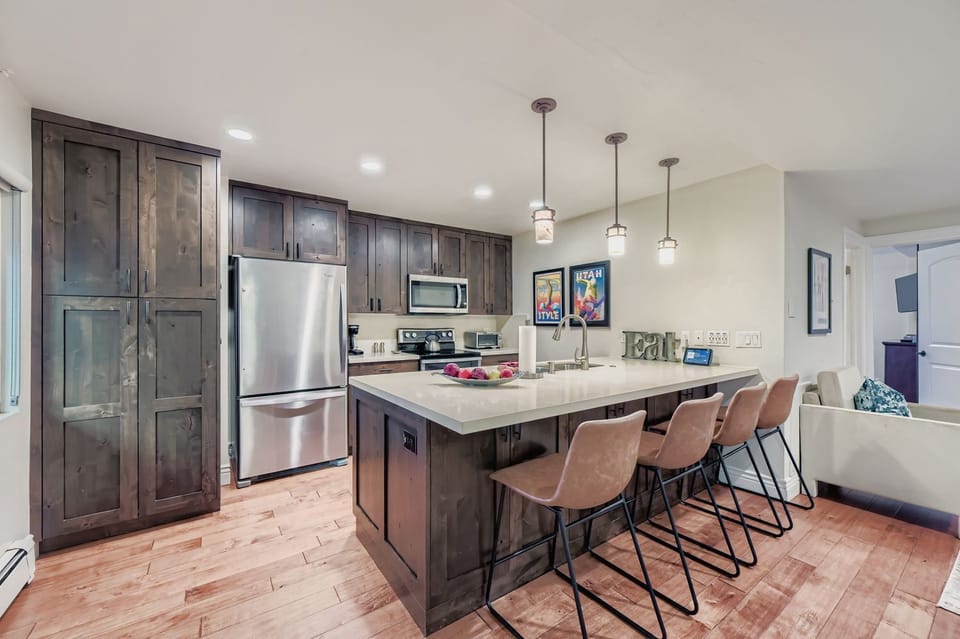 Your fully equipped kitchen features dark wood cabinetry, stainless steel appliances, and a spacious island with seating for casual dining and meal prep.