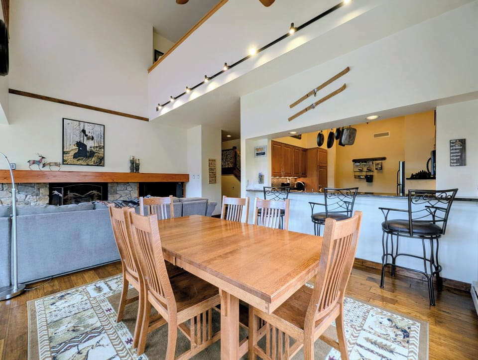 Unwind in this open-concept living space with soaring ceilings, warm wood accents, and cozy fireplace. Your dining table seats everyone comfortably, while the full kitchen and breakfast bar await your culinary adventures.