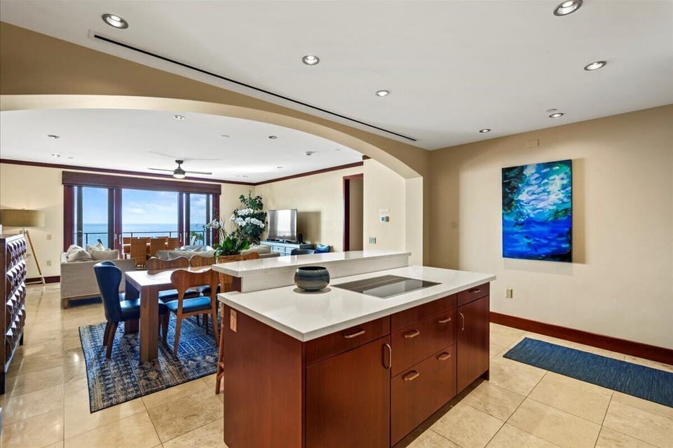 Your open-concept kitchen flows seamlessly into the dining and living areas, where ocean views through large windows frame your perfect tropical getaway.