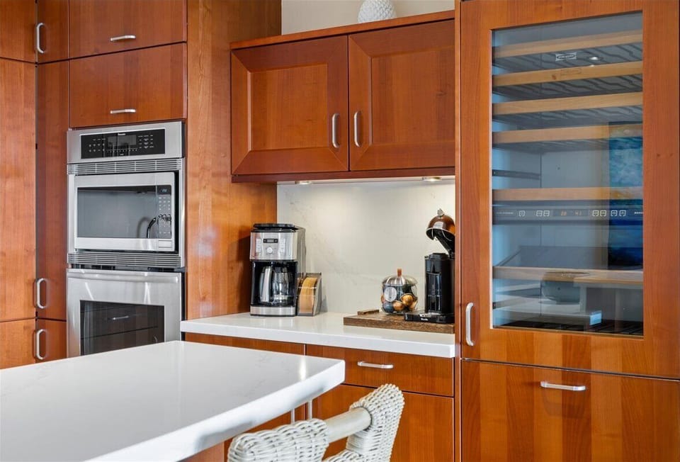 Your fully equipped kitchen features sleek stainless steel appliances, beautiful wood cabinetry, and a coffee station ready for your morning brew.