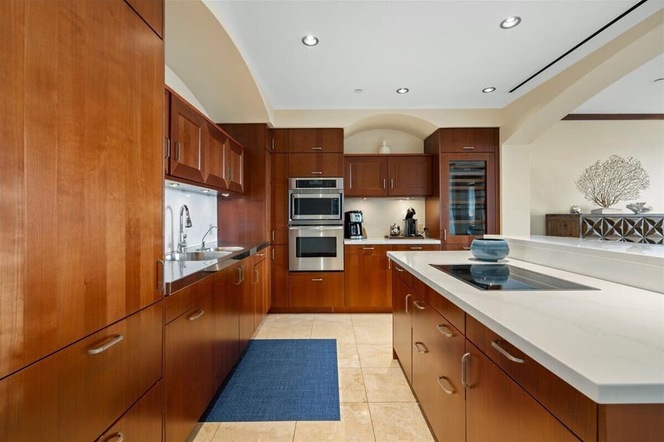 Step into your gourmet kitchen where rich wood cabinetry meets pristine countertops. Prepare meals with top-tier appliances, including double ovens and a wine fridge, all bathed in natural light.