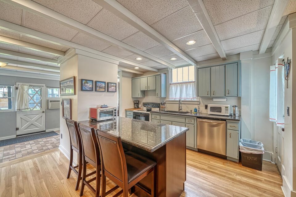 The kitchen in Nita's place features a granite breakfast bar, twin deep-tub composite sinks, and a new refrigerator and dishwasher for modern cooking amenities in this historic home.