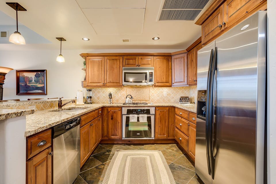 Your fully equipped kitchen awaits with granite counters, stainless appliances, and warm wood cabinets for memorable meal preparation.