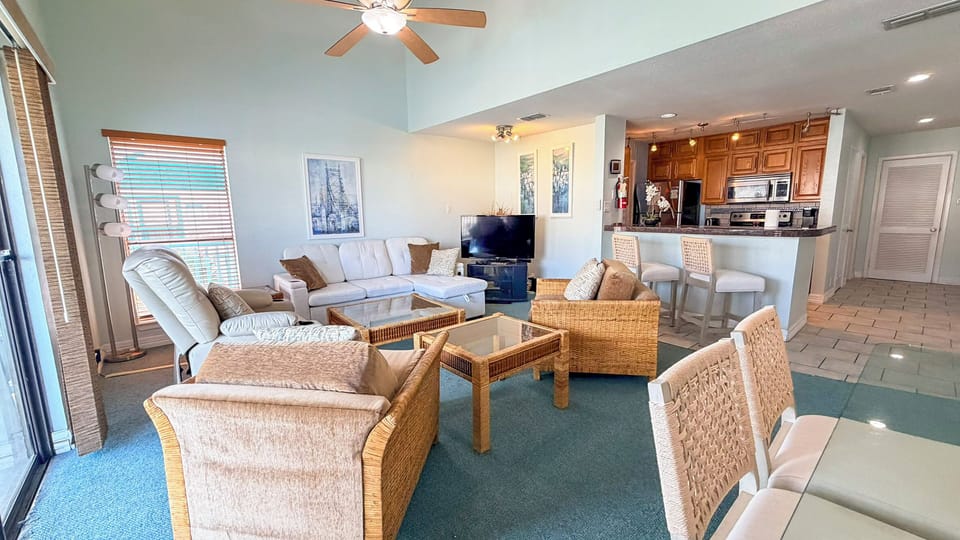 Relax in your spacious open-concept living area with plush seating, modern kitchen, and coastal decor creating the perfect home base.