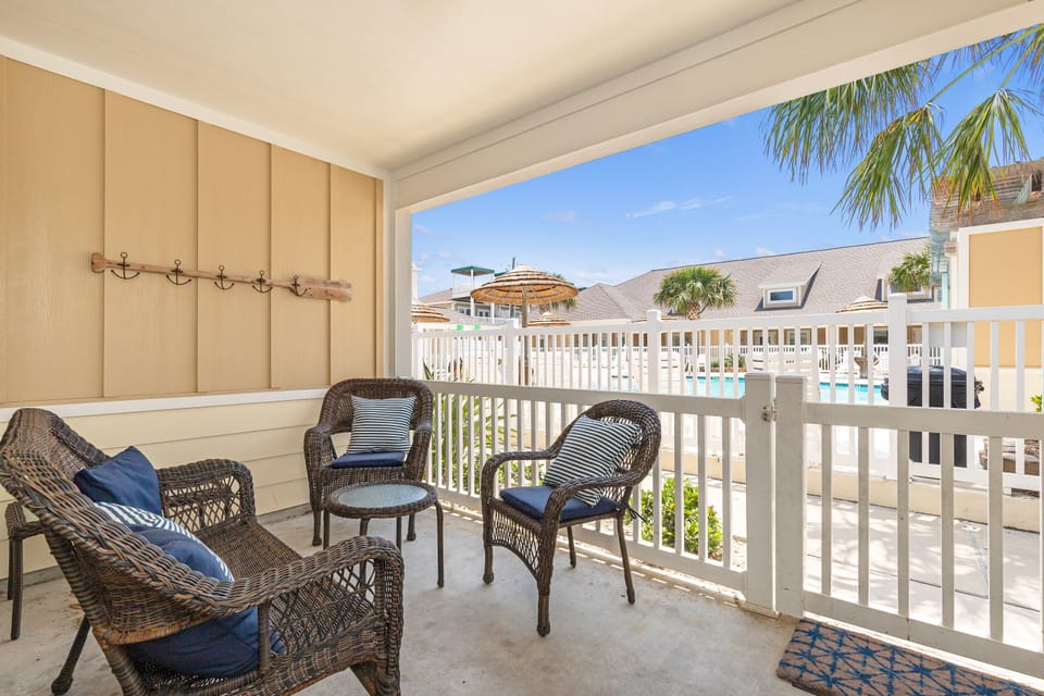 Relax on your private patio with comfortable wicker seating and stunning pool views framed by swaying palm trees.