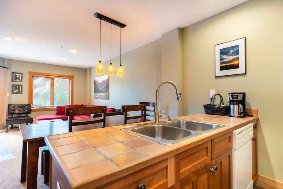 Your open-concept kitchen flows seamlessly into the living area, with warm pendant lights creating the perfect ambiance for cooking and entertaining.