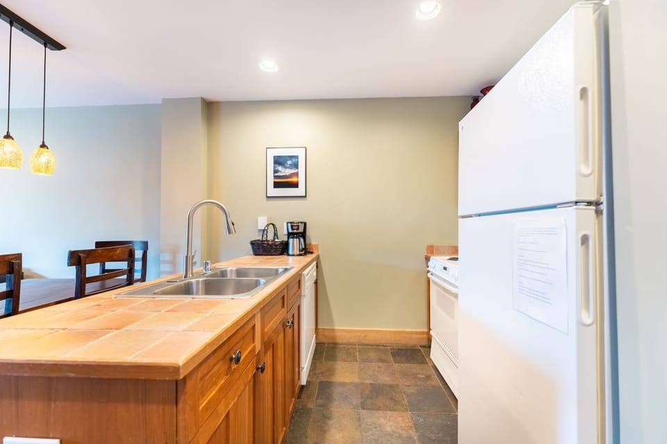 Your fully equipped kitchen features warm wood cabinets, modern appliances, and a cozy breakfast bar where you can prepare meals and start your mornings.
