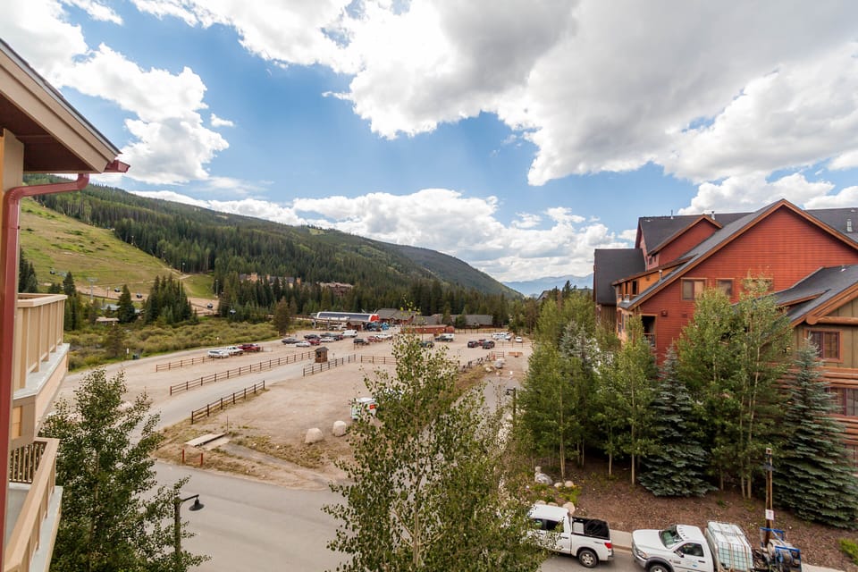 Mountain resort setting with forested slopes and alpine village buildings creating a scenic mountain getaway atmosphere.