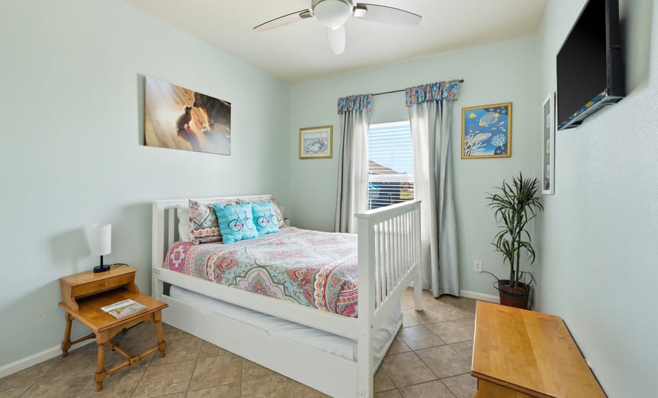 Bedroom — full bed with trundle, mint walls, bicycle pillows, beach art & wall-mounted TV