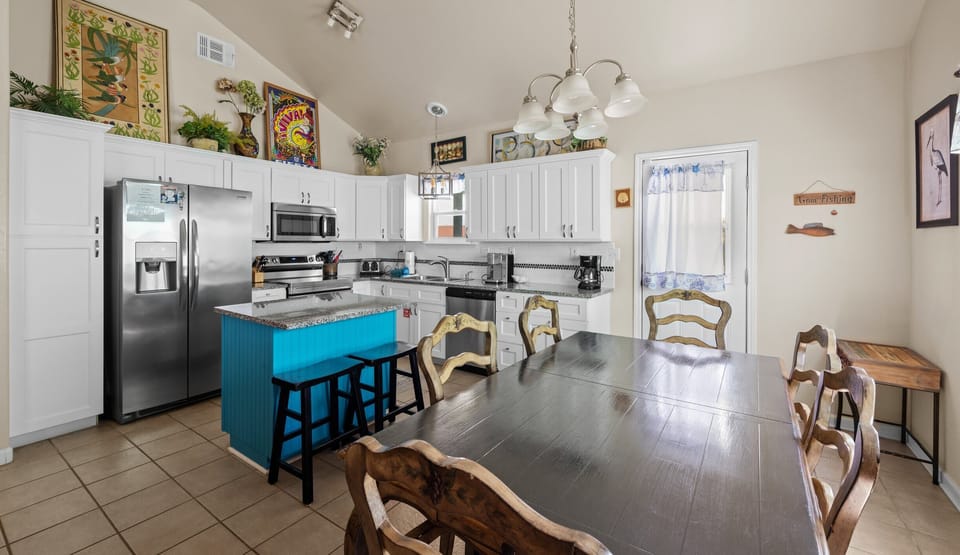 Kitchen & dining — turquoise island with bar stools, dark wood table & stainless appliances