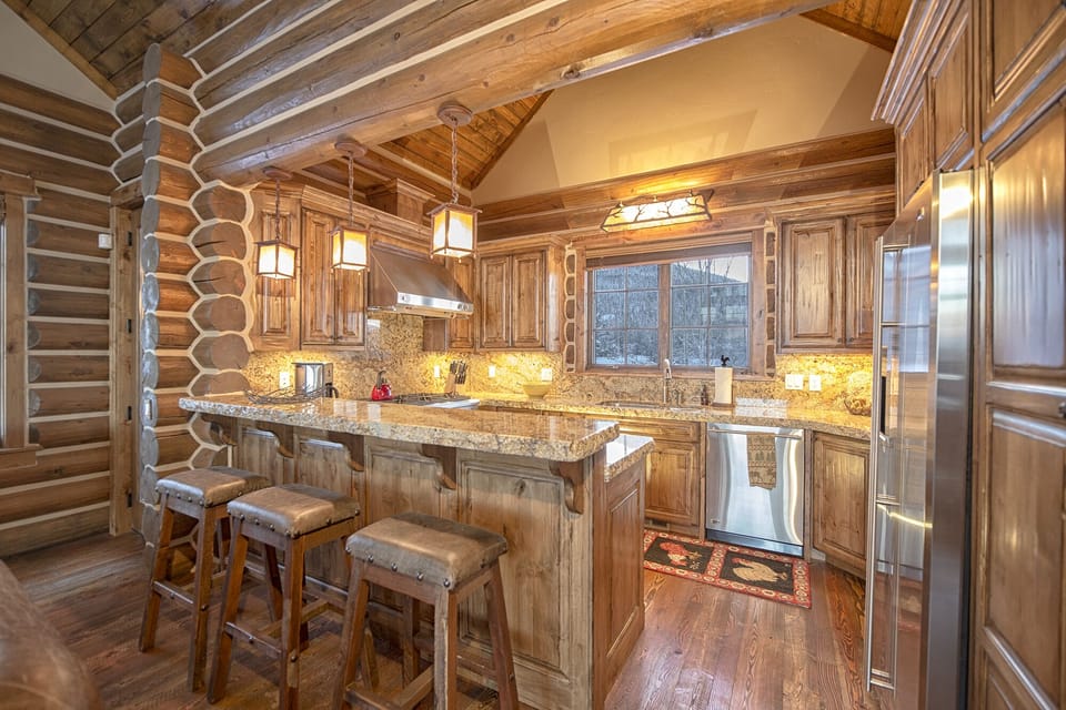 Step into your dream rustic kitchen where warm wood embraces you from floor to ceiling. You'll love preparing meals with granite countertops, premium appliances, and cozy pendant lighting creating the perfect mountain retreat atmosphere.