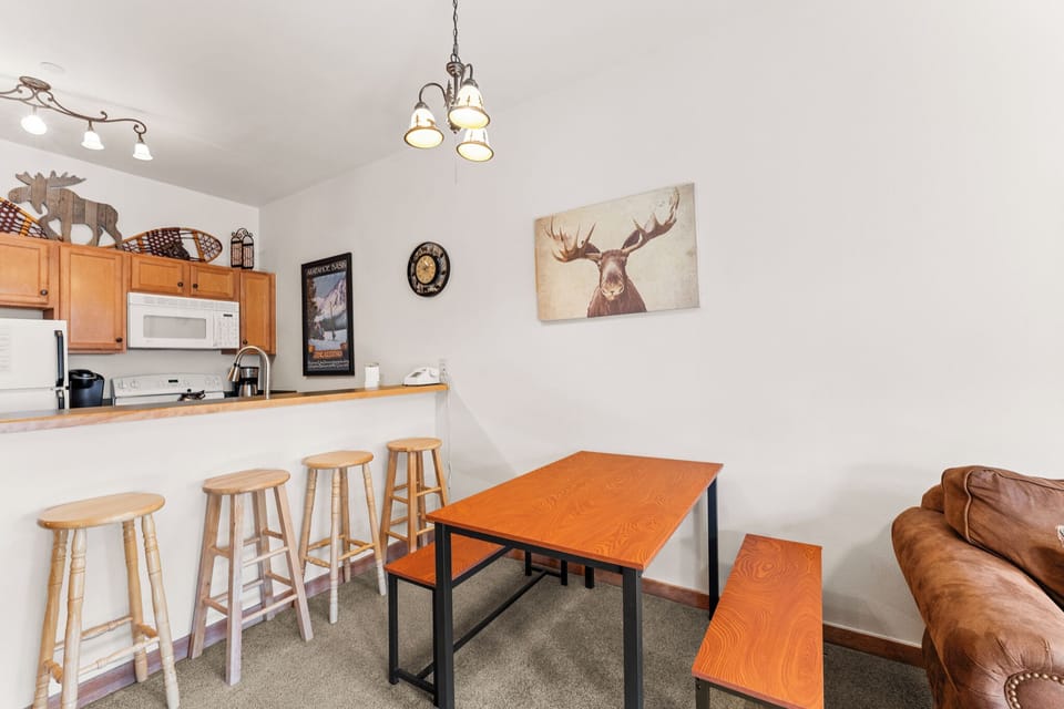 Your cozy mountain retreat features a modern kitchen with breakfast bar and rustic dining space, perfect for sharing meals together.