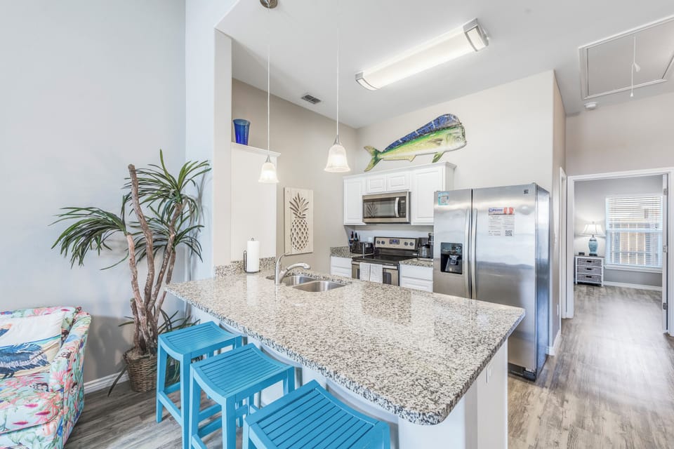 Your open kitchen features granite counters, stainless appliances, and coastal-themed touches that make cooking feel like a beach vacation.
